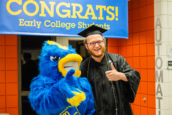 graduate posing with Community college mascit blue bird