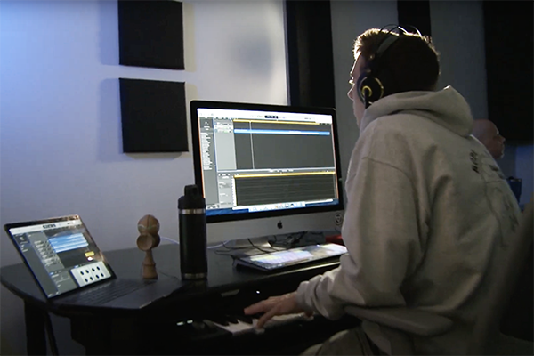 Student with headphones on as they work on a computer