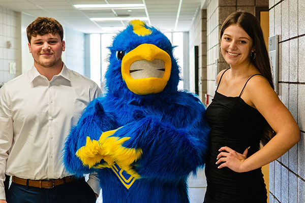 students pose with MCC mascot of a blue bird