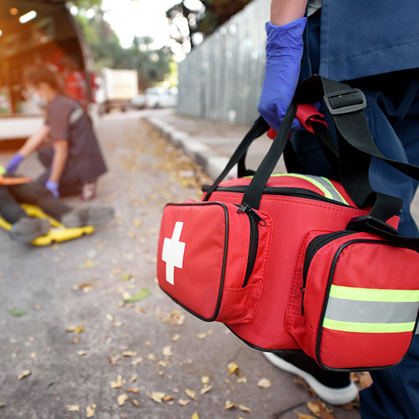 First responder walks while holding Emergency Medical First aid kit bag.