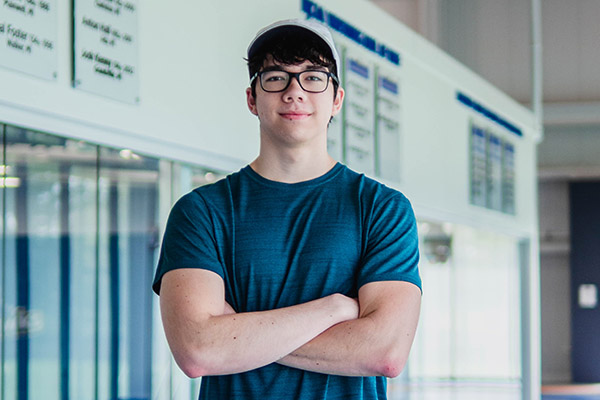 Young man crosses arms and smiles.