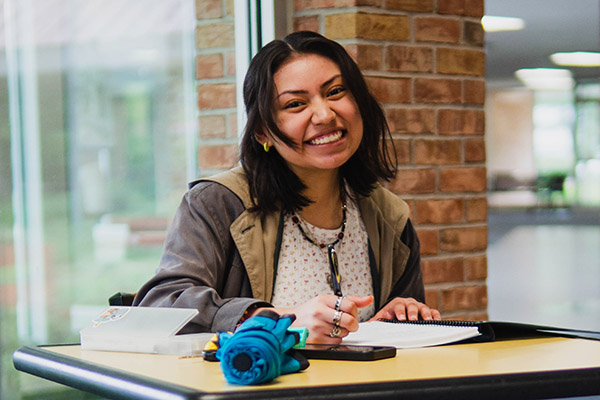 Female student smiles while working at a desk.