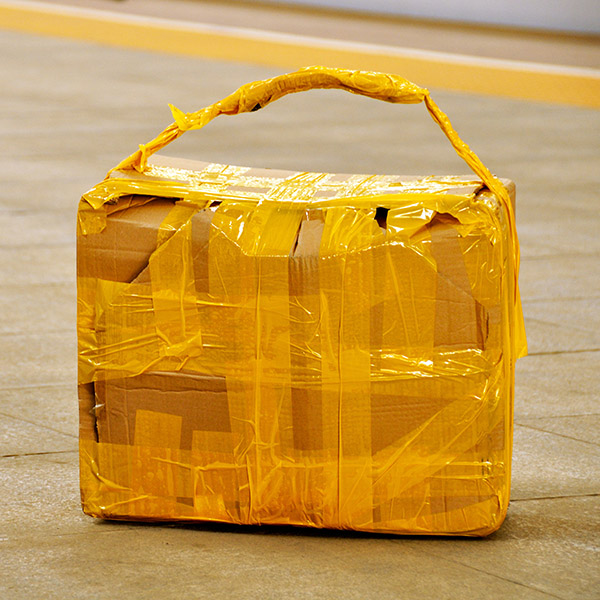 Suspicious looking box with yellow tape abandoned on sidewalk.