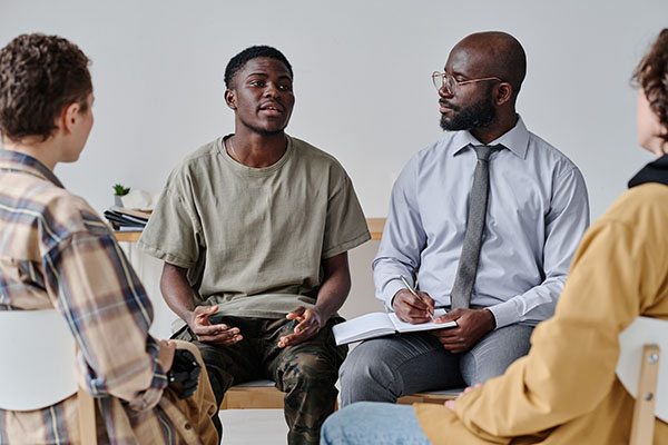 African American teenage boy talking about his problems to psychiatrist and support group