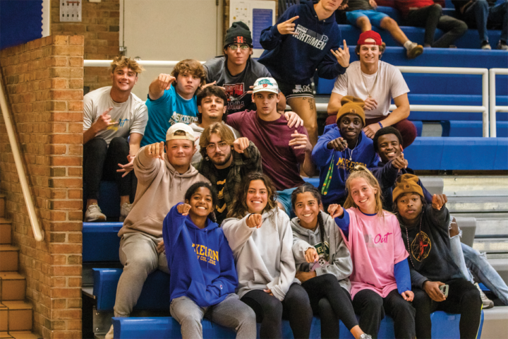 Group of diverse students pointing at camera. They look like they're enjoying their time at a MCC girls volleyball game. I'm sure they think MCC is awesome, cause it is