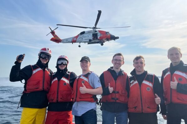 Group of maritime engineers on the water with helicopter flying overhead