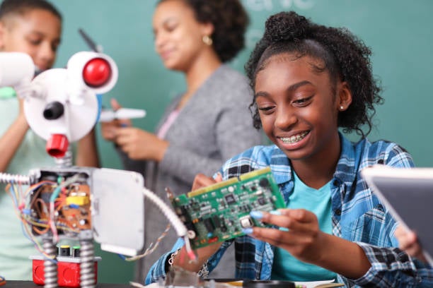An African-American girl with braces looks at a computer part
