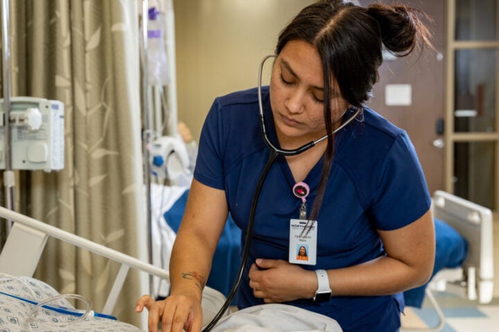 Nurse listening to heart of patient.